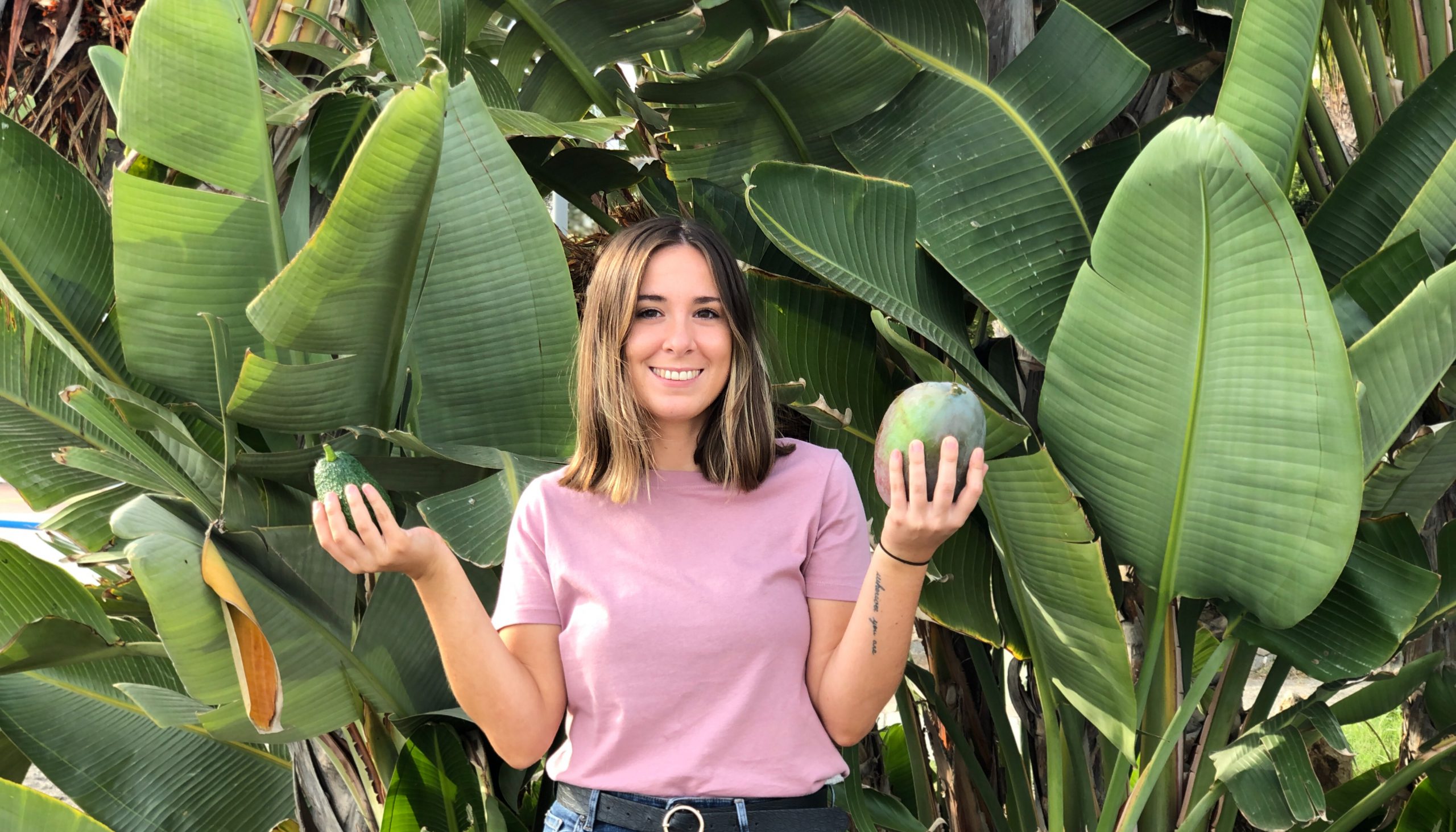 La agricultora María Martínez con un aguacate y un mango en cada mano