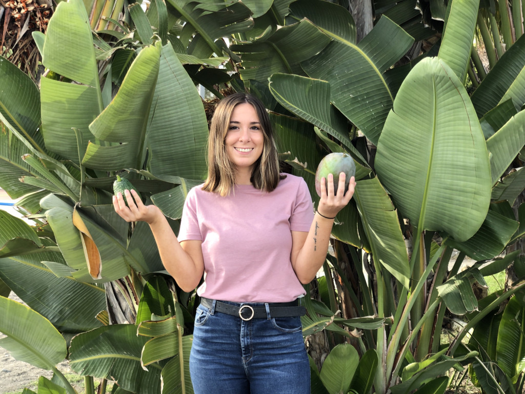 La agricultora María Martínez con un aguacate y un mango en cada mano