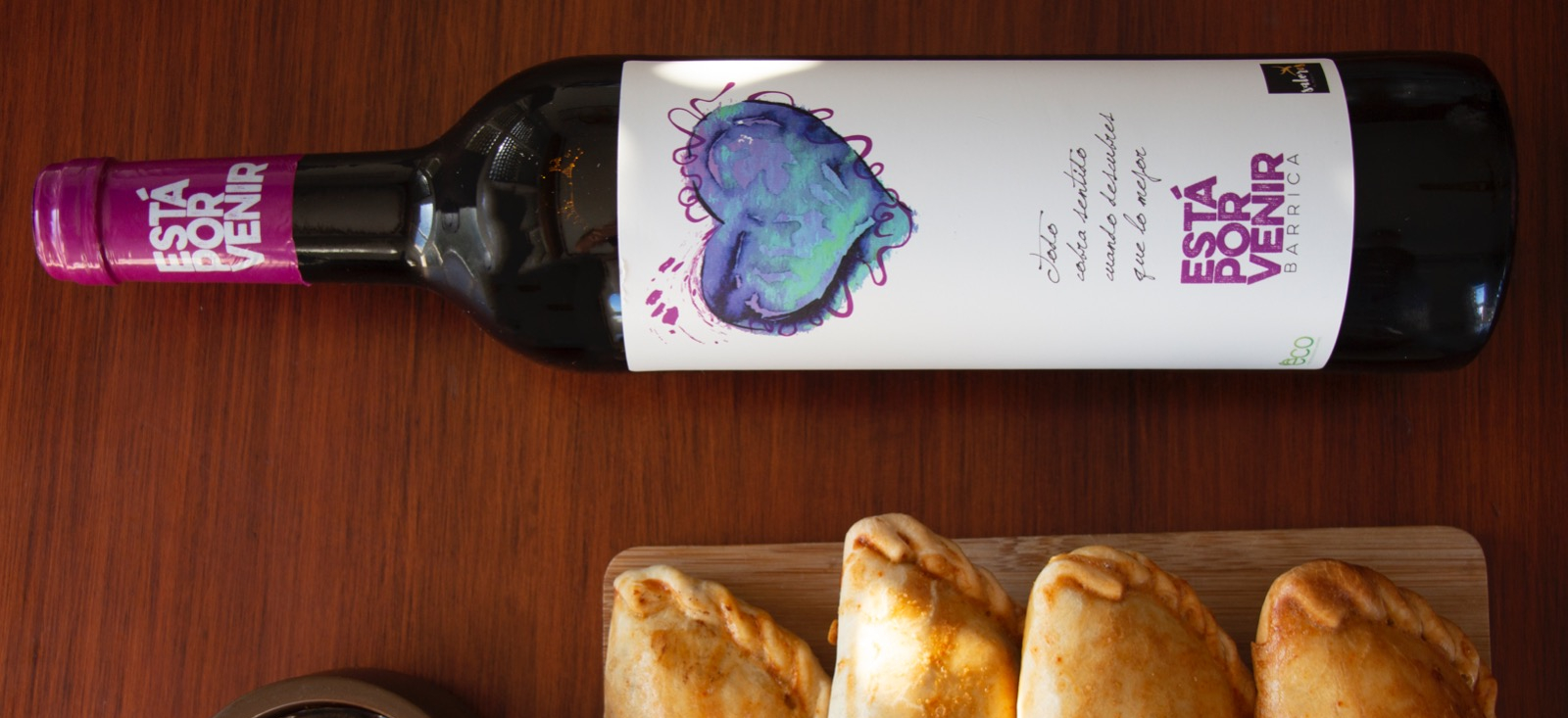 Bottle of red wine with empanadas on a board