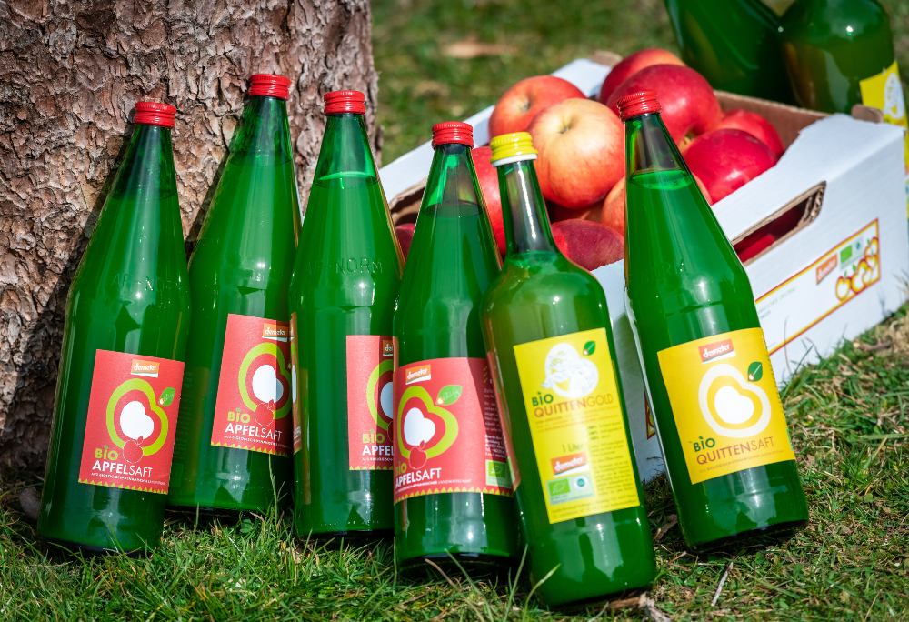 Bottles of apple and quince juice with a cardboard box of apples