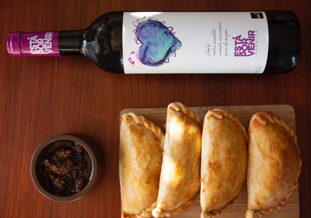 Bottle of red wine with empanadas on a board