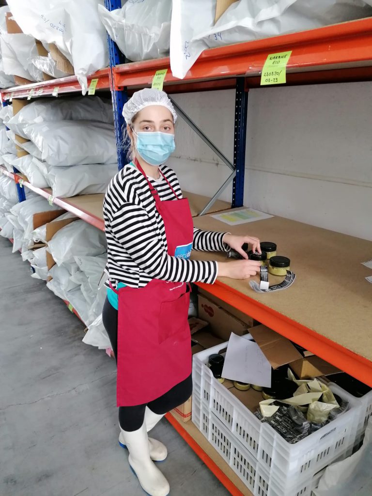 A person with a mask and apron in a warehouse