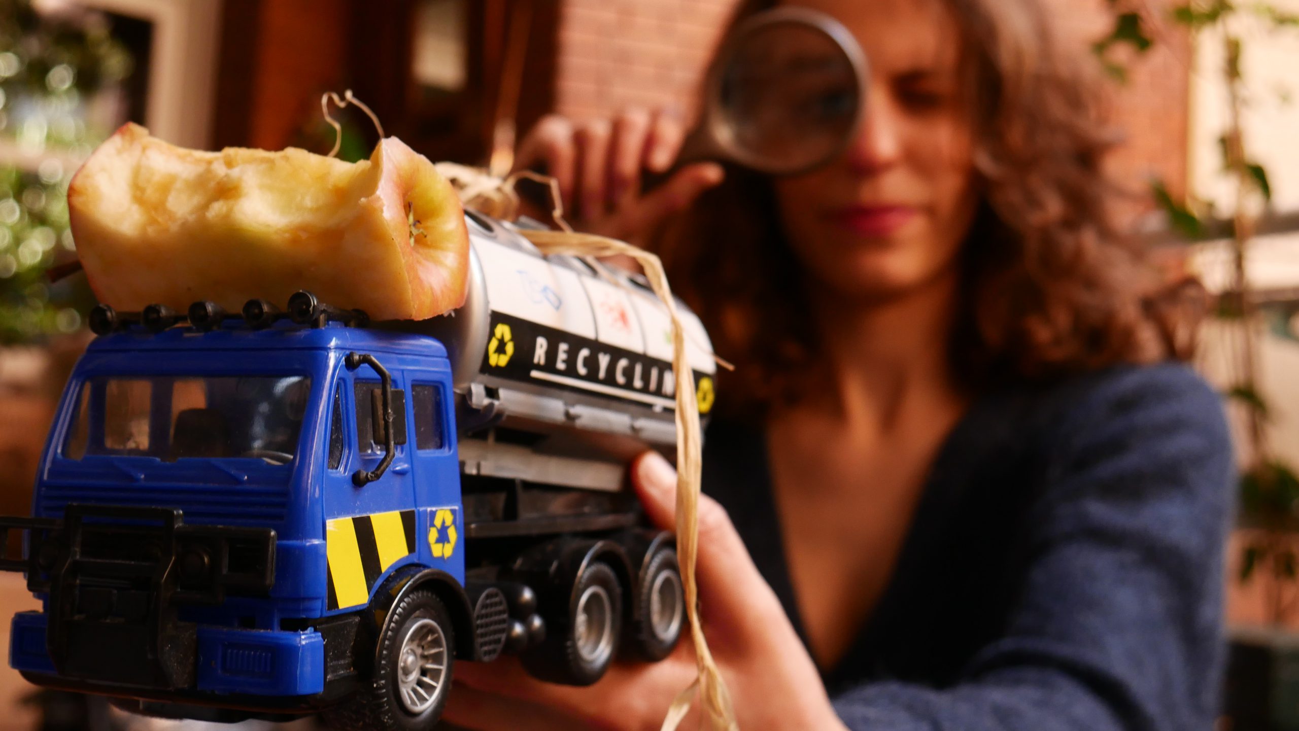 Une femme tient dans sa main un camion de recyclage avec un trognon de pomme