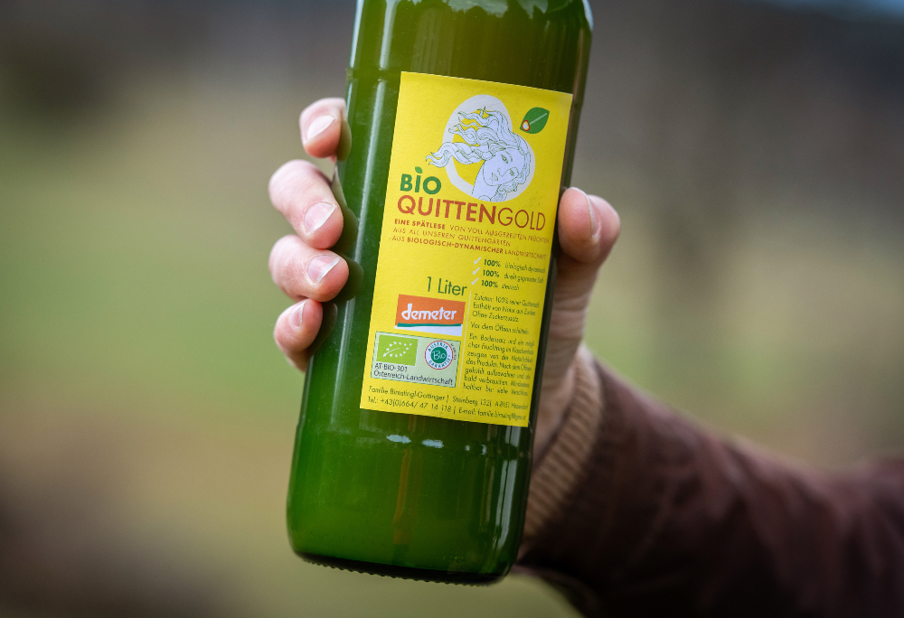 Eine Hand, die eine Glasflasche mit Quittensaft hält