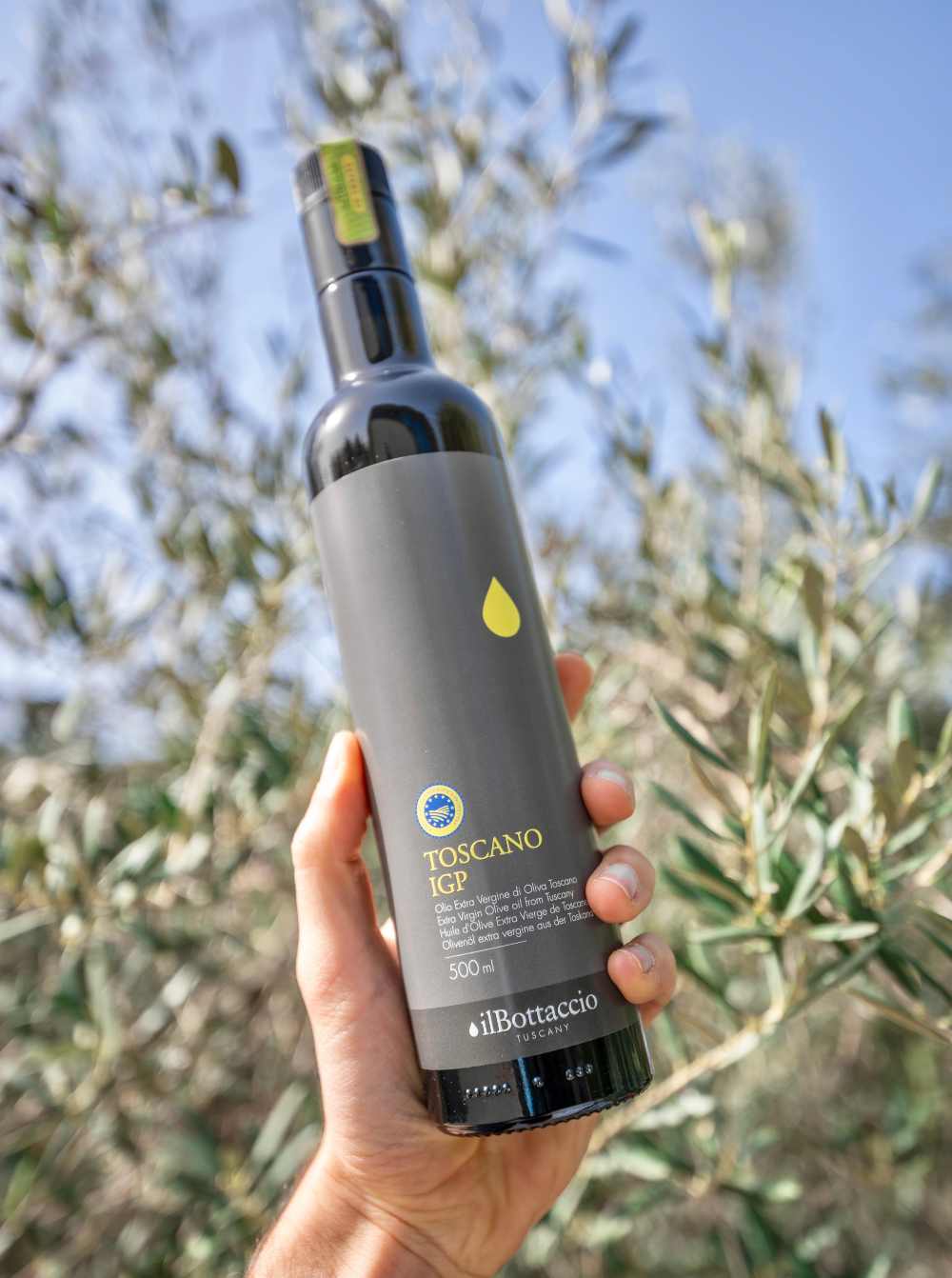 Eine Hand, die eine Flasche extra natives Olivenöl Il Bottacio hält
